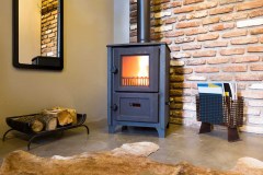 Modern wood burning stove inside cozy living room with rustic brick walls and bear skin on the floor.