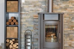 Wood fired stove with fire-wood and fire irons. With brick wall.